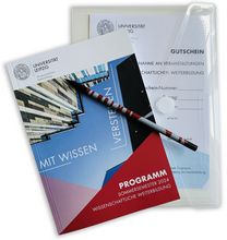Farbfoto: Detailaufnahme der Programmbroschüre der Wissenschaftlichen Weiterbildung und eines Gutscheins
