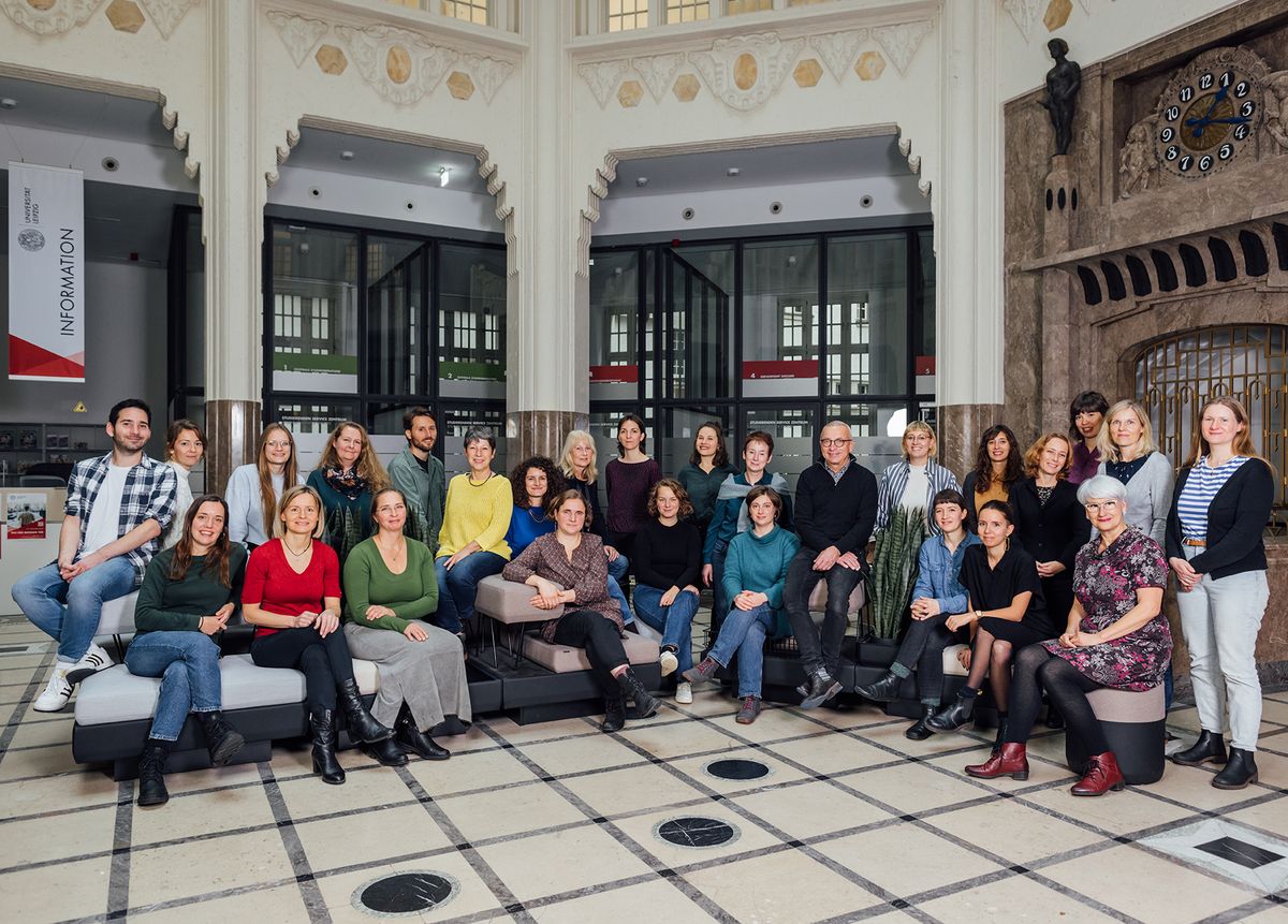 zur Vergrößerungsansicht des Bildes: Farbfoto: Mitarbeitende der Stabsstelle Internationales sitzen bzw. stehen zusammen im Foyer des SSZ der Universität Leipzig