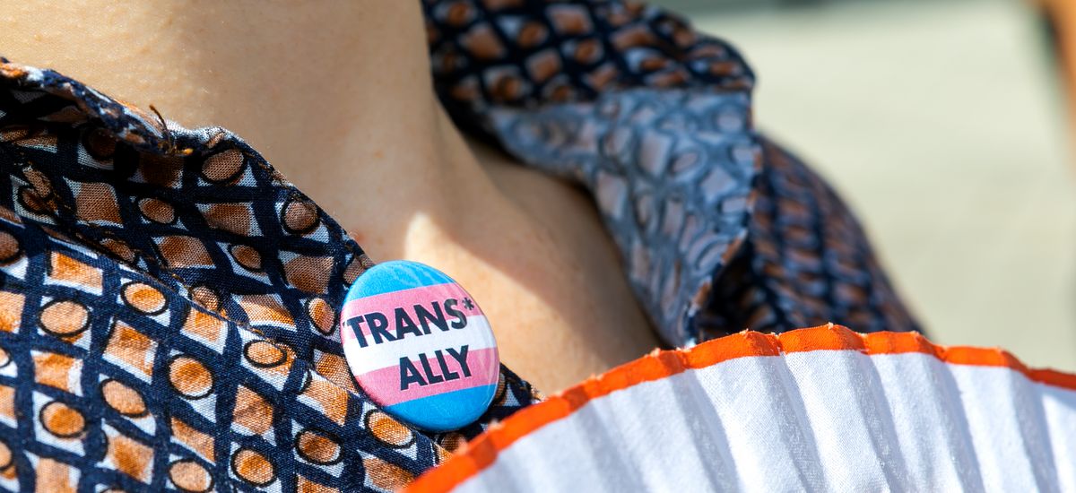 Am Kleidungsstück einer Person ist ein Button befestigt mit der Aufrschrift "trans ally"