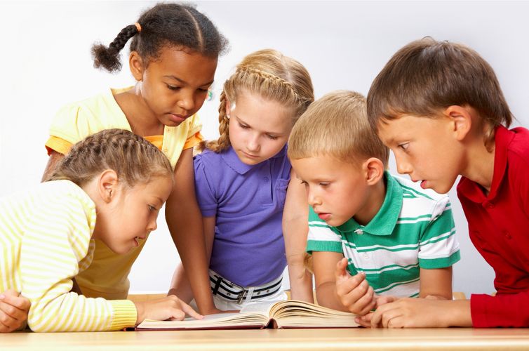 Symbolbild: Fünf Kinder schauen gemeinsam in ein Buch.