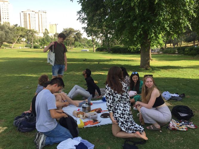 Gruppe von Menschen bei sonnigem Wetter auf der Wiese eines Parks in Jerusalem