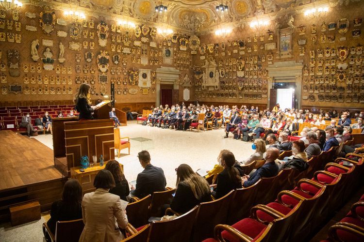 Viele Menschen sitzen in der prächtig geschmückten Aula der Universität Padua und hören einer Rednerin zu