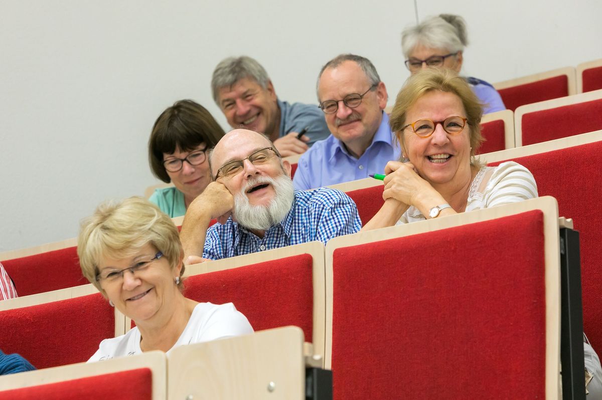 Lächelnde Teilnehmerinnen und Teilnehmer des Seniorenkollegs im Audimax