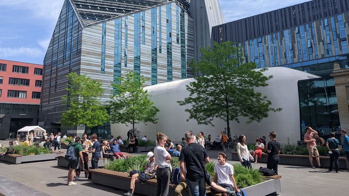 Studierende sitzen im Leibniz-Forum und genießen die Sonne.