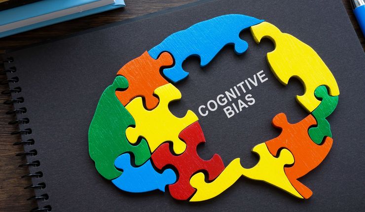 Stilisiertes Holzpuzzle eine Gehirns, in der Mitter Puzzle fehlen ein paar Teile und in der Lücke steht Cognitive Bias