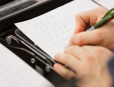 Student schreibt Mathematikformeln auf ein Blatt, Foto: Christian Hüller