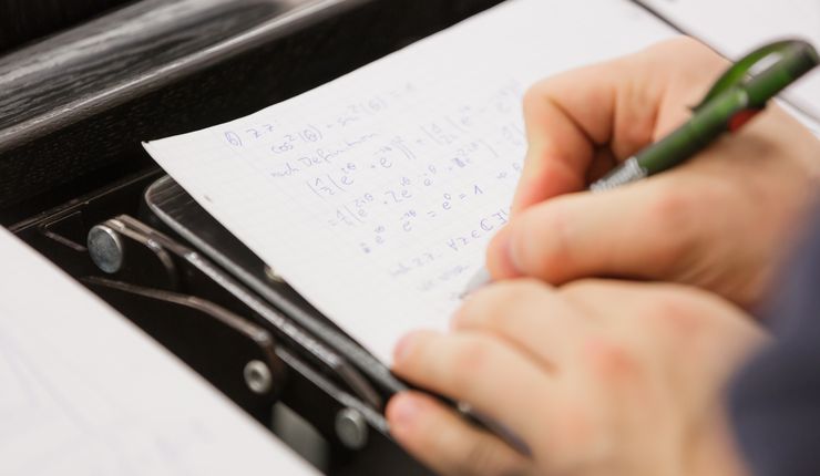 Student schreibt Mathematikformeln auf ein Blatt, Foto: Christian Hüller
