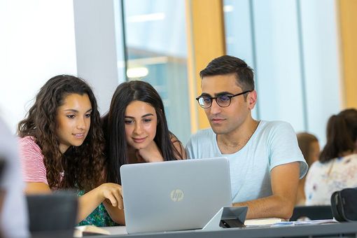 Symbolbild: Drei Studierende arbeiten gemeinsam an einem Laptop.