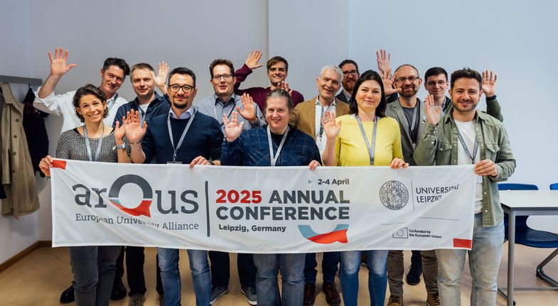Zu sehen ist eine kleine Gruppe von Menschen, die ein Banner von Arqus hochhalten.