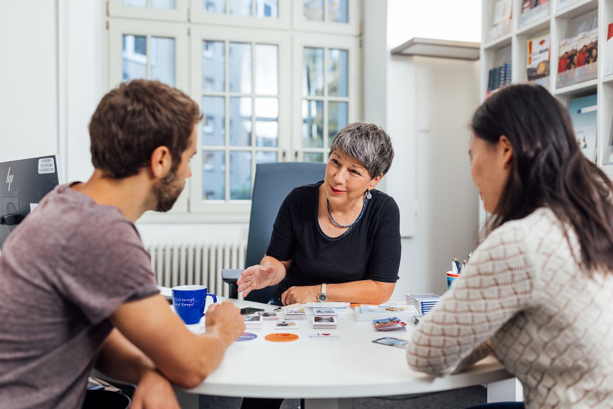 enlarge the image: Two people sitting at a desk opposite a counsellor