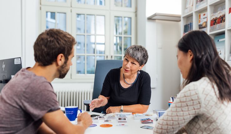 Zwei Menschen sitzen zum Beratungsgespräch mit einer Mitarbeiterin der Stabsstelle Internationales an einem Schreibtisch