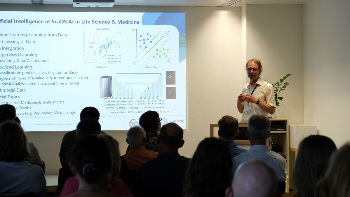 zur Vergrößerungsansicht des Bildes: Dr. Christian Martin erklärt vor dem Publikum die Arbeit mit Künstlicher Intelligenz in der Krebsforschung