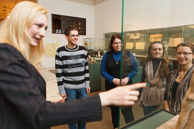 Dozentin und Studierende stehen im Halbkreis um einen Schaukasten, Foto: Christian Hüller