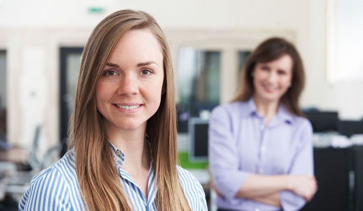 Sujetbild: Zwei Frauen stehen in einem Büro und schauen in die Kamera.