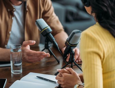 Zwei Menschen sitzen sich in einer Interviewsituation vor Mikrofonen gegenüber, Foto: colourbox.com