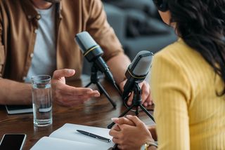 Zwei Menschen sitzen sich in einer Interviewsituation vor Mikrofonen gegenüber, Foto: colourbox.com