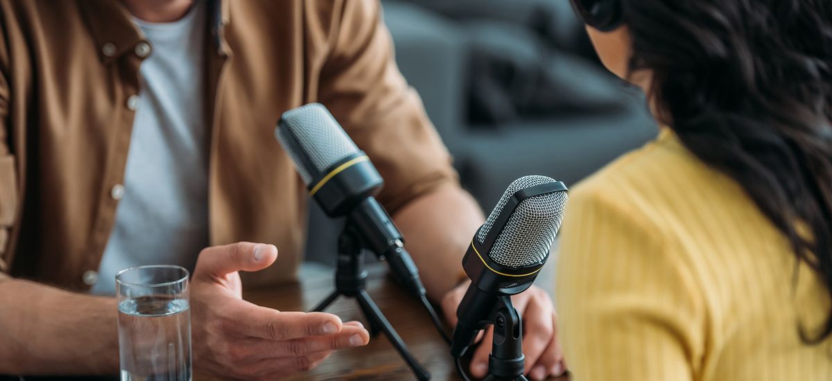 Zwei Menschen sitzen sich in einer Interviewsituation vor Mikrofonen gegenüber, Foto: colourbox.com