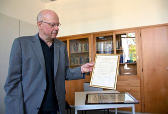 Dr. Thomas M. Goerlich hält ein golden gerahmtes Original-Staatsexamen vom 18. Juli 1870 in den Händen. © Universität Leipzig, Fotograf: Anton Stolle 