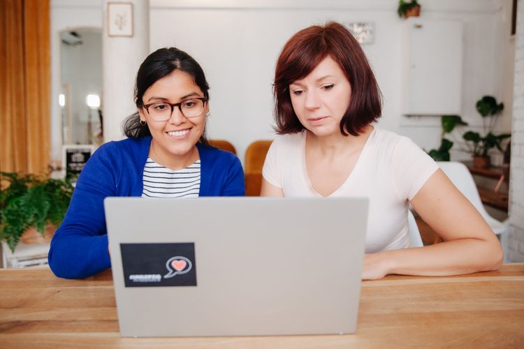 Zwei junge Frauen arbeiten gemeinsam am Laptop.