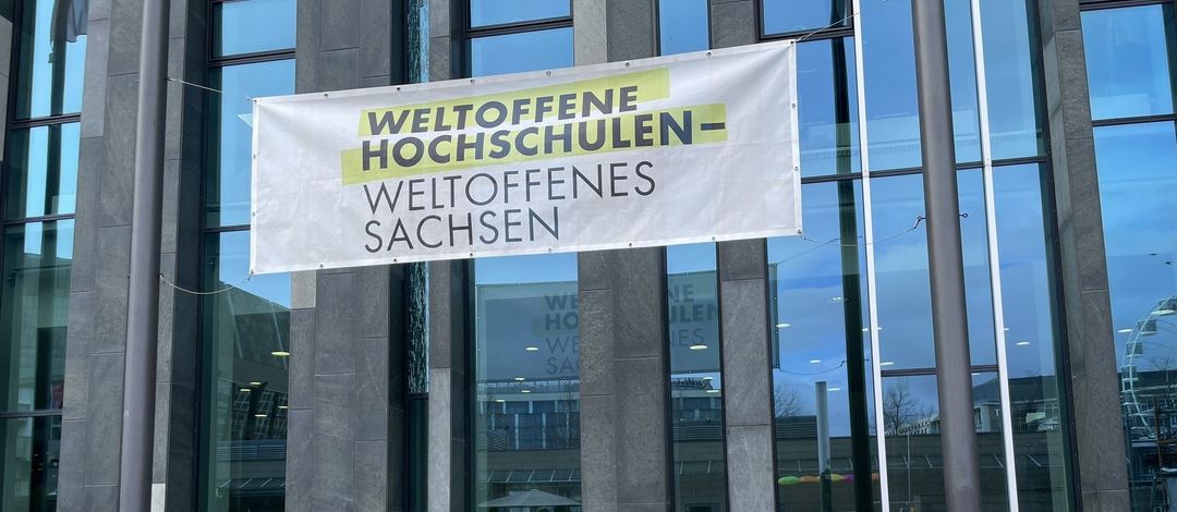 An der Fassade des Palliums hängt ein Banner mit dem Schriftzug "Weltoffene Hochschulen, Weltoffenes Sachsen".