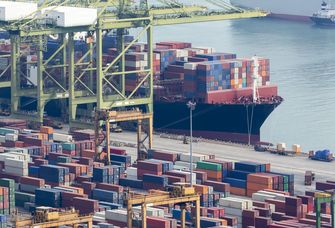 Blick auf einen Containerterminal, im Hintergrund ein Containerschiff am Kai 