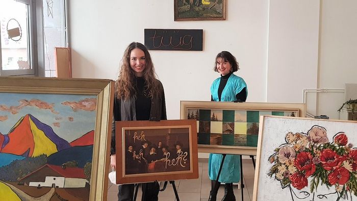 Zwei Studentinnen stehen zwischen Staffeleien mit Gemälden