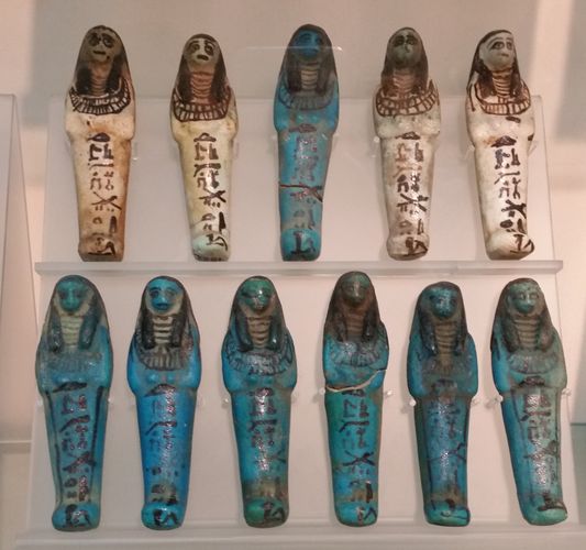 Uschebti-Figuren in 2 Reihen übereinander, in verschiedenen Farben. Foto: Anna Grünberg