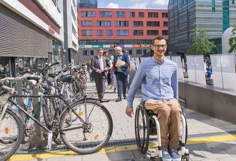 Auf dem Bild ist ein junger Rollstuhlfahrer im Innenhof des Campus Augustusplatz zu sehen.