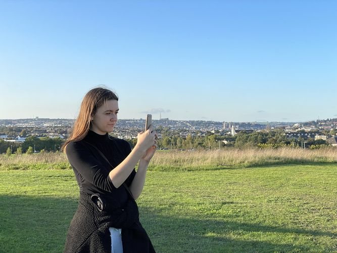 Eine Frau fotografiert den Tramore Valley Park in Cork. Im Hintergrund ist die Stadt kork zu sehen.