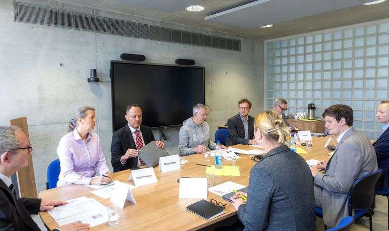 Gesprächspartnerinnen und Gesprächspartner an einem großen Besprechungstisch. 