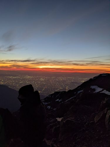 Blick von einem Berg auf eine beleuchtete Stadt bei Nacht