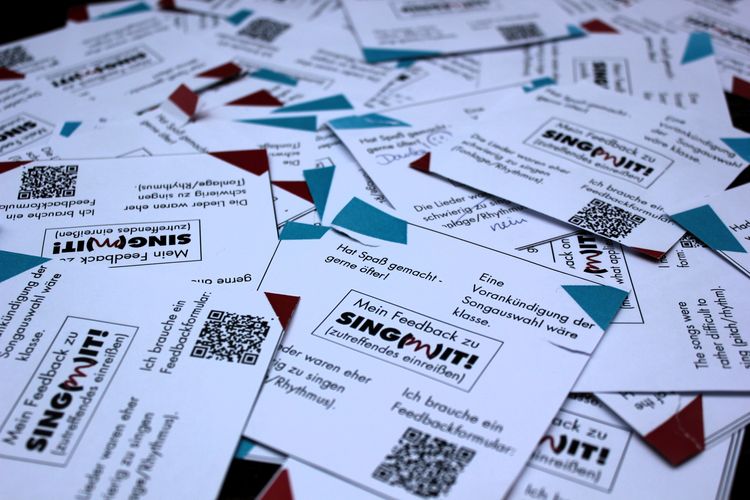 Viele Feedbackzettel. Auf ihnen stehen Feedbackantworten. Zutreffendes haben die Teilnehmer:innen eingerissen. Eine eingerissene Antwort lautet: „Hat Spaß gemacht – gerne öfter!“ eine andere „ Eine Vorankündigung der Liedauswahl wäre klasse“.