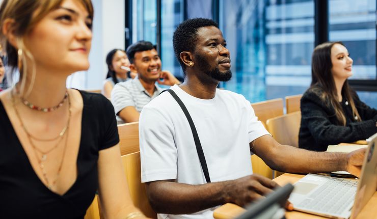 Colour photo: 5 people sit facing forwards in a seminar room.