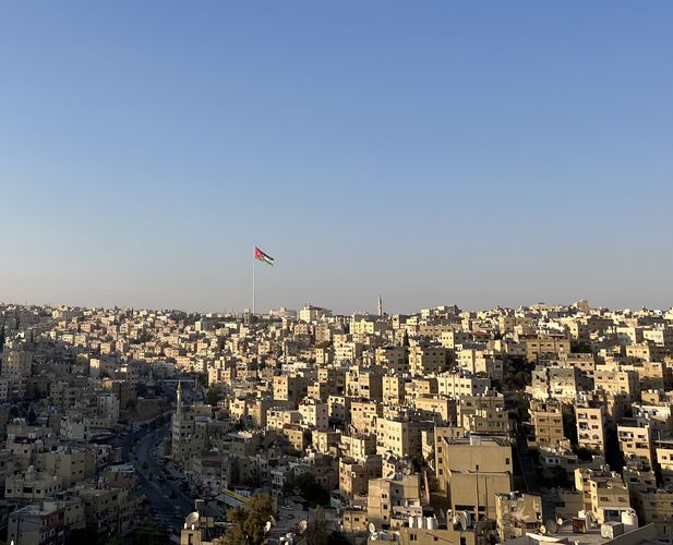 Das Foto zeigt einen Blick auf die jordanische Hauptstadt Amman. Man sieht sehr viele Dächer vor einem blauen Himmel. 