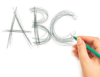 Die Buchstaben ABC auf ein weißes Blatt mit Bleistift geschrieben, eine Hand hält den türkisfarbenen Stift.
