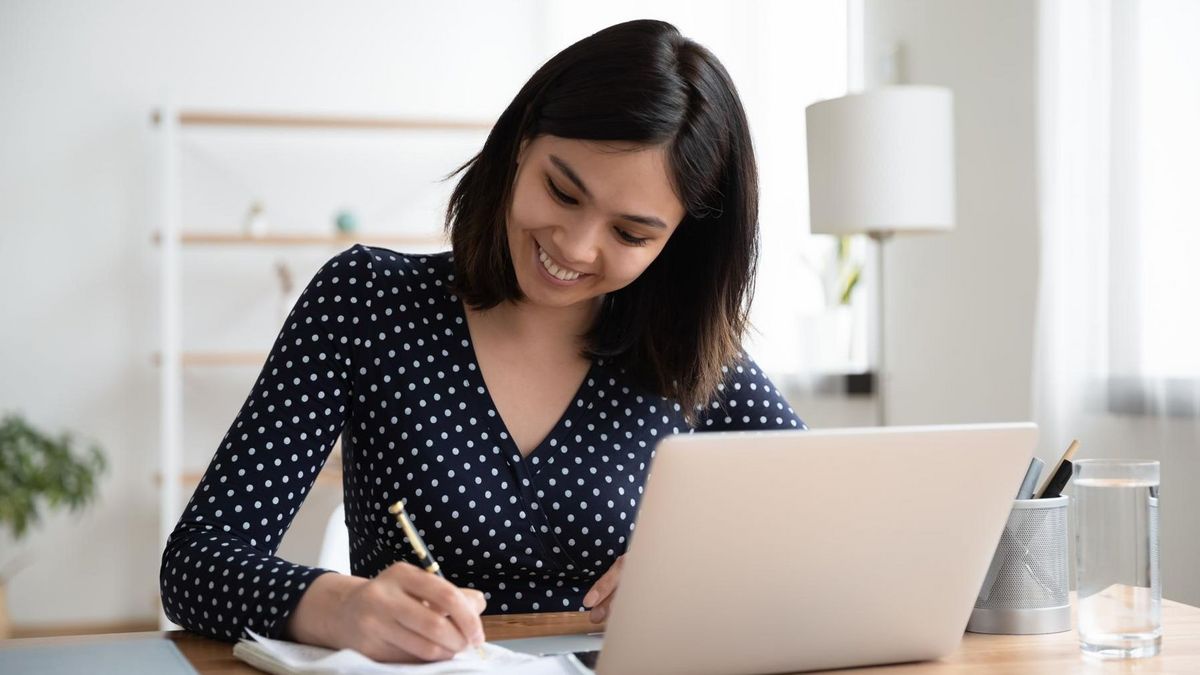 Eine junge Frau am Schreibtisch, vor ihr ein Laptop