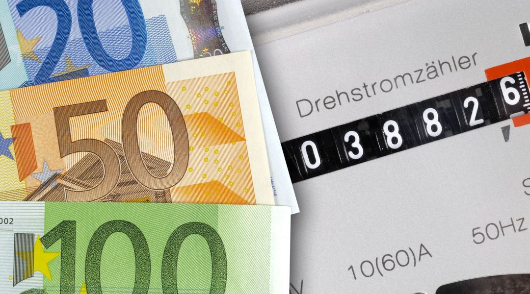 Symbolbild: Mehrere Geldscheine verdecken einen Stromzähler.