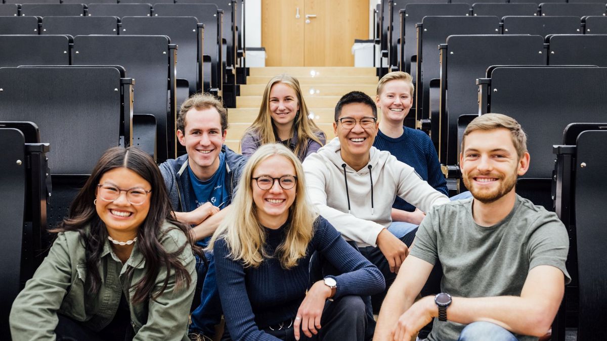 Gruppenbild Studienbotschafter:innen im Hörsaal auf dem Boden sitzend, Foto: Christian Hüller