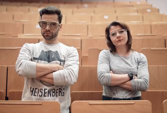 Moderator Jack Pop und Marika Kandler stehen in den Sitzreihen eines Hörsaals