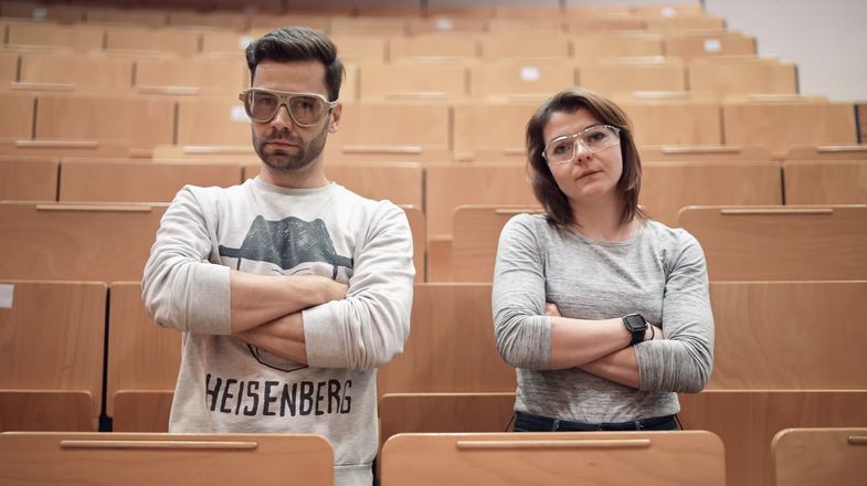 Moderator Jack Pop und Marika Kandler stehen in den Sitzreihen eines Hörsaals