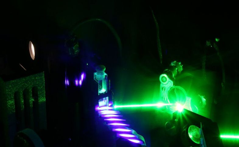 Das Bild zeigt ein chemisches Experiment mit violettem und grünem Licht.