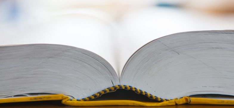 Ein in der Mitte aufgeschlagenes Buch liegt auf dem Tisch