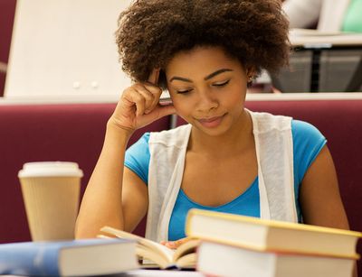 Junge Frau sitzt über Büchern, Foto: Colourbox