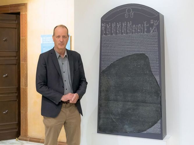 Dietrich Raue links neben der Replik des Rosetta-Steins stehend