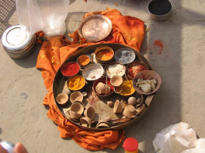 Metallschalen mit verschiedenfarbigen Pulvern und Gewürzen auf einem Holztablett, das auf einem orangefarbenen Tuch auf dem Steinfußboden steht, das sind Untensilien für das hinduistische Totenritual Shraddha, Varanasi, Indien, 2011, Foto: Johanna Buß