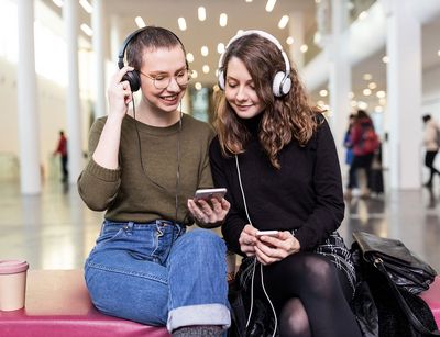 Zwei Studentinnen mit großen Kopfhörern hören in Neuen Augusteum der Uni Leipzig den neuen Podcast "Auf einen Kaffee mit...", Foto: Christian Hüller