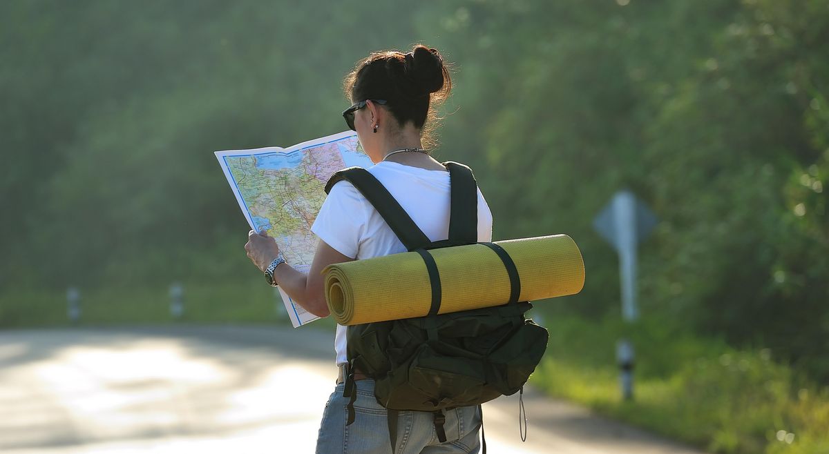 enlarge the image: Young woman with backpack is looking at a map
