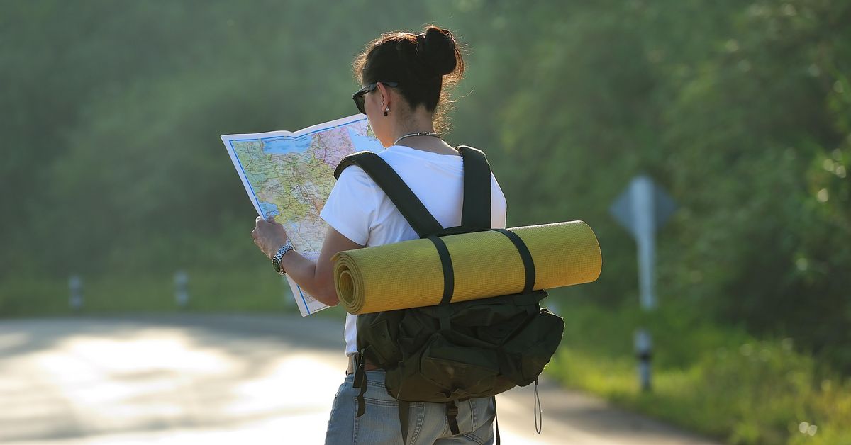 zur Vergrößerungsansicht des Bildes: Junge Frau mit Rucksack schaut sich Landkarte an