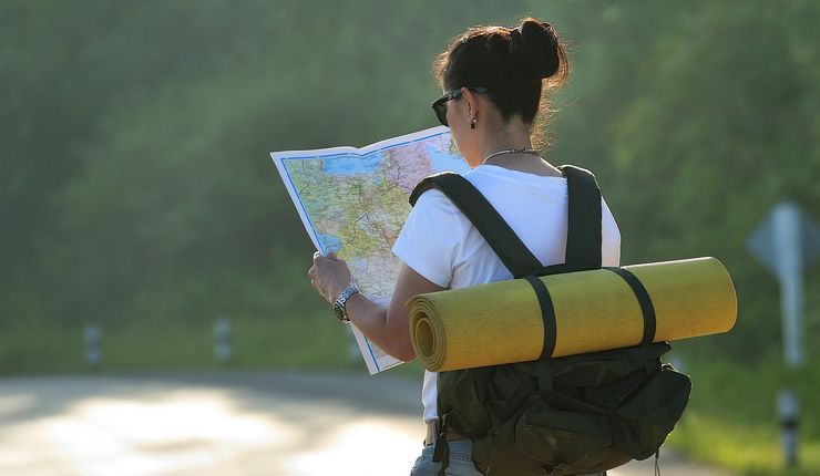 Junge Frau mit Rucksack schaut sich Landkarte an