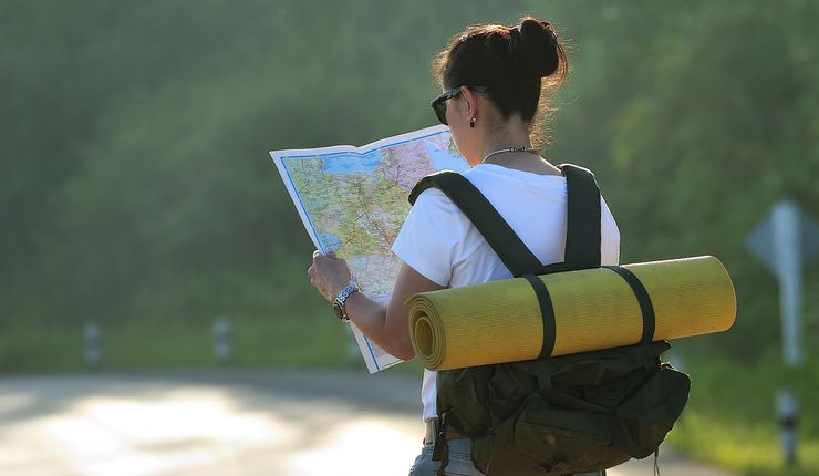 Junge Frau mit Rucksack schaut sich Landkarte an